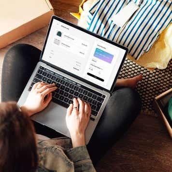 Young woman doing online shopping with laptop sitting on the floor at home