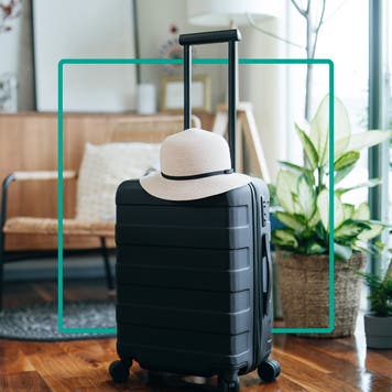 Design element featuring a travel suitcase with a sun hat sitting on top