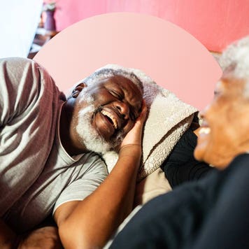Two people laughing in bed.