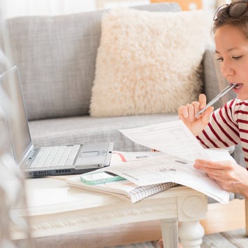 Mixed race woman paying bills on laptop - stock photo.