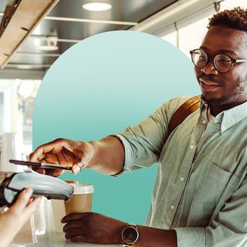Young black man smiling while paying with a credit card at a coffee shop