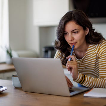 Young woman using a laptop while working from home - stock photo