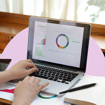 Woman sitting at a desk looking at a laptop with charts and graphs on the screen.