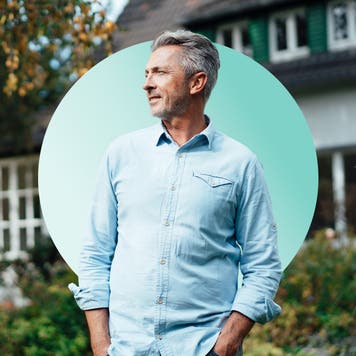 Middle-age man standing in front of his home looking at something in the distance