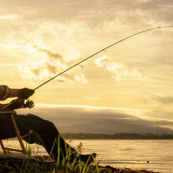 A man fishes along the waterfront at sunrise
