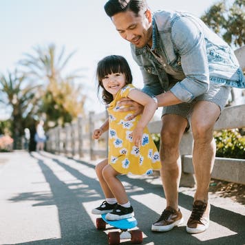Dad helps young daughter ride skateboard, Father's Day tax tips