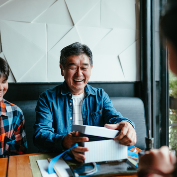 Older man receiving a gift from his family at a restaurant.
