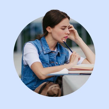 white brunette woman holding a black pencil and studying over a concrete surface