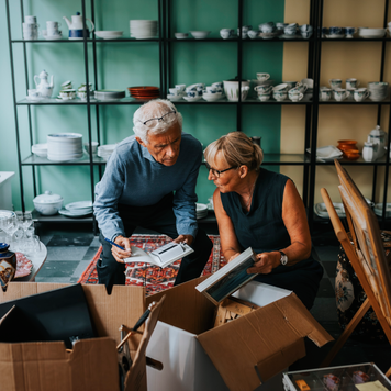 An older couple opens boxes of inventory as they set up their small shop.