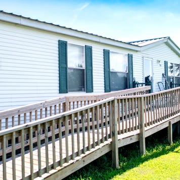 The side of a mobile home with a wheelchair ramp leading to the front door