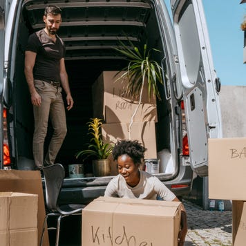 A couple loads moving boxes into a moving van