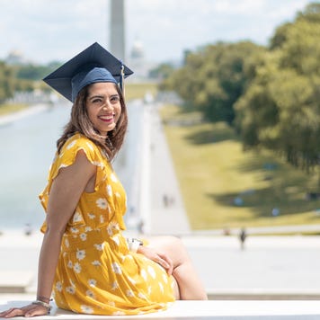 A graduating student sits on the steps overlooking the west mall in Washington DC