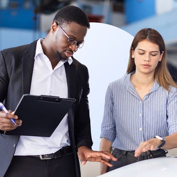 man and woman in car repair shop standing near car discussing its condition