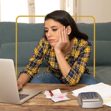 Woman staring glumly at her laptop with her chin perched on one hand.