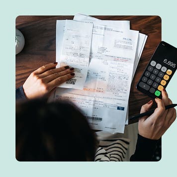 Above angle view of woman calculating bills on calculator