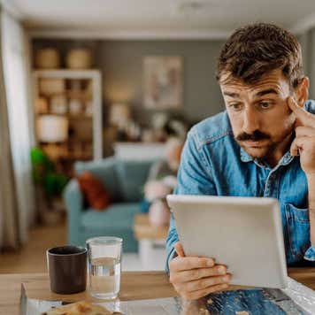 A man who looks worried stares at his table at the kitchen counter.