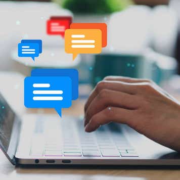 Close up shot of a woman typing on a laptop while comment bubbles float up from the keyboard.