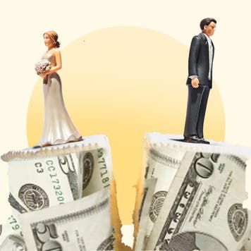 A wedding cake wrapped in money is split in two with a bride on one half and a groom on the other half.