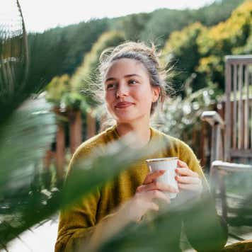 Woman with morning cup of coffee, sitting on patio and enjoying moment for herself.