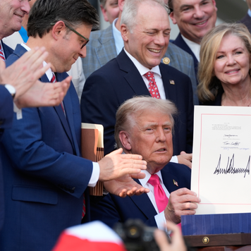 President Donald Trump holds up the "One, Big Beautiful Bill" Act that was signed into law during an Independence Day military family picnic.