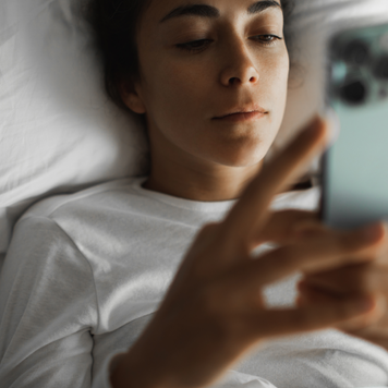 Woman looking at her phone in bed.