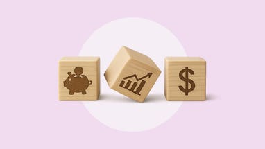 Three light blonde colored wooden blocks in a row with the following painted images: a piggy bank with a coin goin into it's slot, a bar graph and line rising from left to right, and a dollar sign.