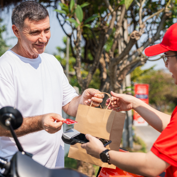 A delivery person delivers food to a customer's house.