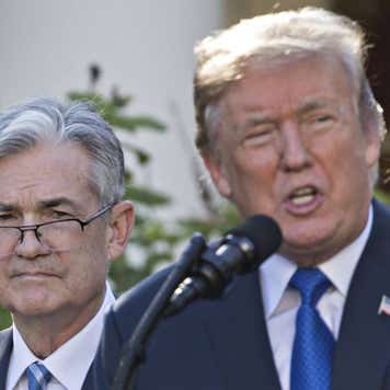 Federal Reserve Chair Jerome Powell standing behind President Donald Trump.