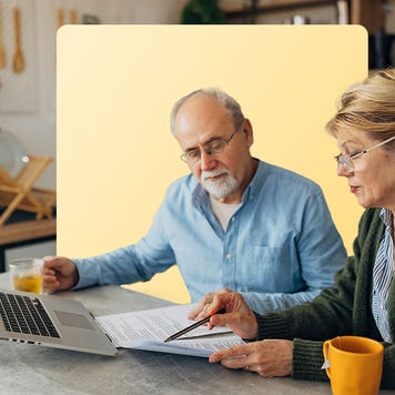 An older couple look at a laptop computer and documents to review their retirement plan.