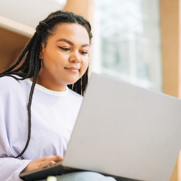 Young Black woman using a silver laptop.