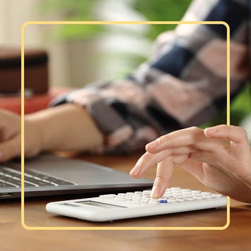 A person uses a calculator and tablet.