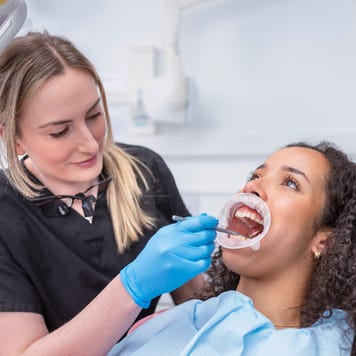 A dentist works in the open mouth of a patient