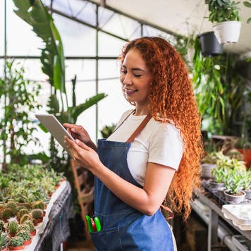 Woman working with digital tablet in plant nursery greenhouse