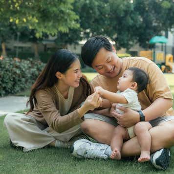 Couple holding a baby in a park.
