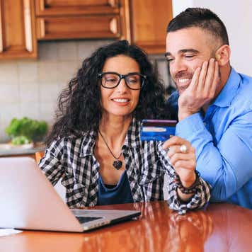 Happy couple using credit card and laptop at home