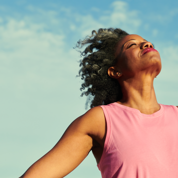 Woman standing on a windy beach with the sky in the background.