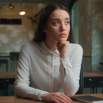 Young woman sitting at table looking thoughtful.