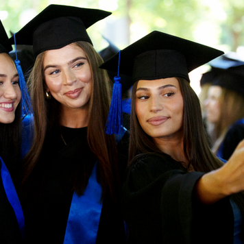 Three female college graduates take a selfie in caps and gowns