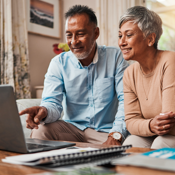 Mature couple sitting at a laptop, planning their finances.