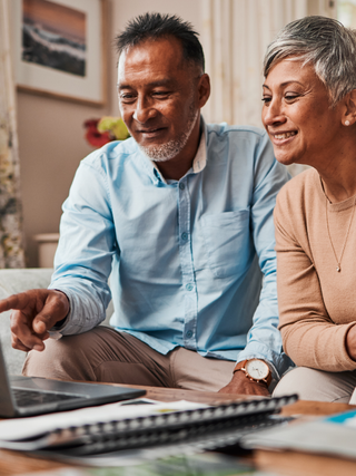 Mature couple sitting at a laptop, planning their finances.