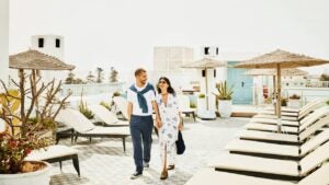 Wide shot couple walking on rooftop deck of luxury tropical resort