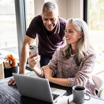 Couple looking at a laptop and a smartphone.
