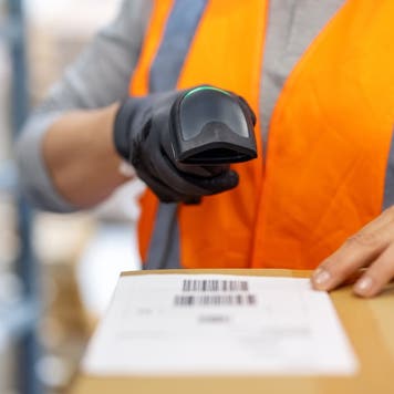 Close-up of a woman warehouse worker scanning package with bar code scanner