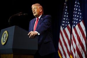President Donald Trump speaks behind a podim with a U.S. flag in the background