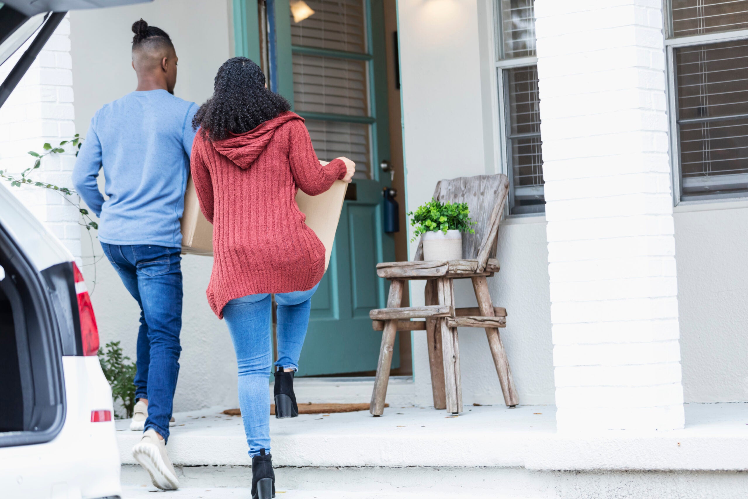 Young couple walks into a new home carrying boxes