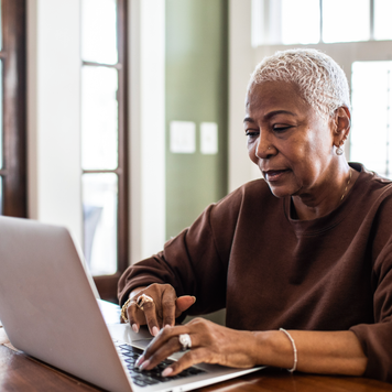 Older woman doing her taxes on her laptop at home.
