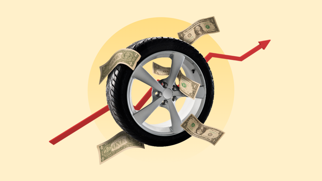 A car tire surrounded by American dollar bills. Behind the tire, there is a red line graph going up and to the right.
