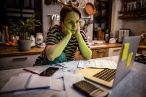 Woman doing her bills in dim light at a kitchen table.