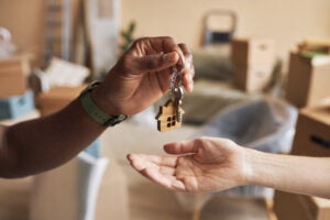 A hand drops house keys into another person's hand