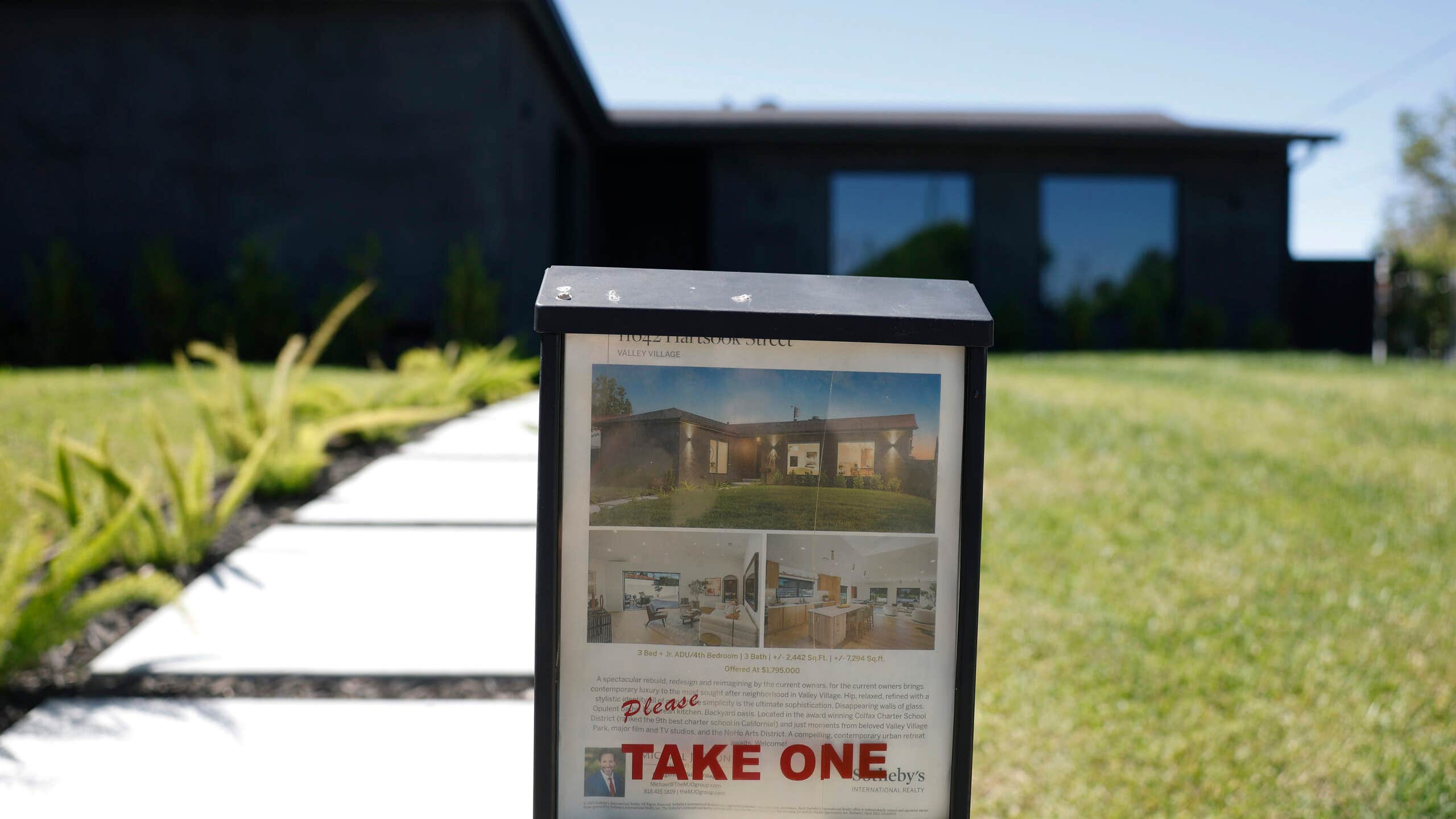 A "Pleast take one" sign in front of a for-sale property.